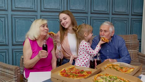 Family-having-lunch-party,-feed-each-other-with-pizza,-laughing,-enjoying-meal-together-at-home