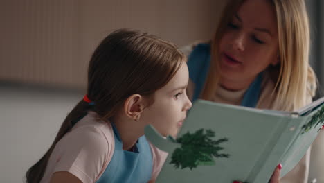 madre cuidadosa está enseñando a su hija preescolar a cocinar leyendo recibo en el libro de cocina