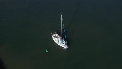 Yate-De-Vela-Con-Una-Larga-Sombra-Navega-En-Su-Motor-A-Lo-Largo-De-La-Boya-Verde-Sobre-Las-Claras-Aguas-Verdes-Del-Mediterráneo