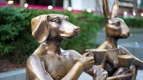 bronze statues of a dog and rabbit holding tea and coffee cups, coffee lover couple, atypical street art