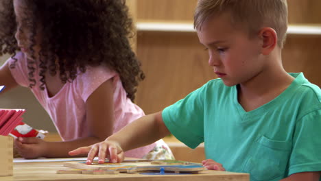 alumnos de montessori trabajando en un escritorio con rompecabezas de forma de madera