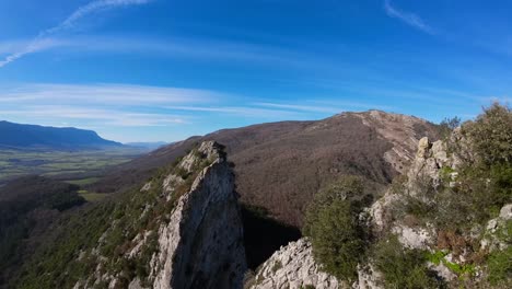 fpv drone aerial image taken from the top of a towering stone mountain, a calming natural image with shades of green, grey, and blue sky