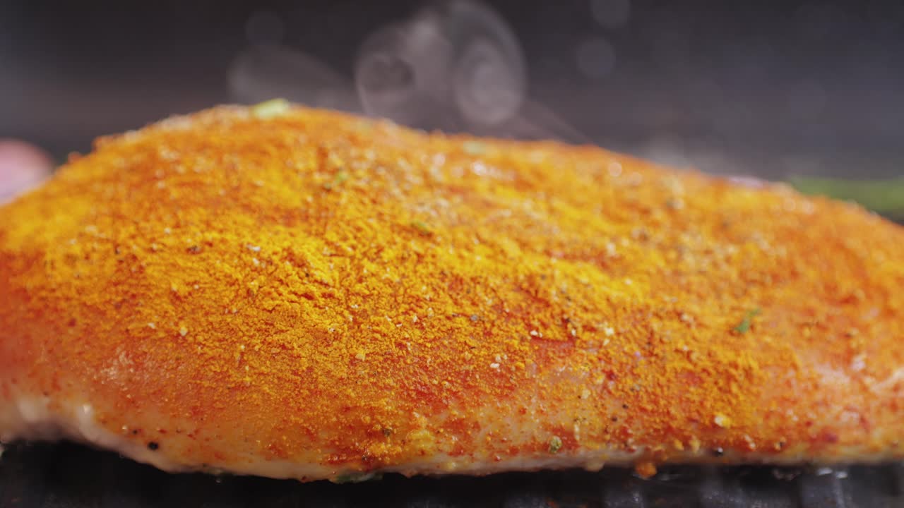 Cooking raw chicken meat in yellow turmeric spice with garlic and greens on grill close-up. Preparing raw food for cooking. Grilled chicken, duck, turkey kebab with vegetables.