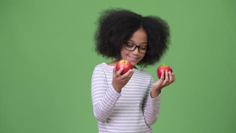 joven africana feliz con cabello afro sosteniendo manzanas