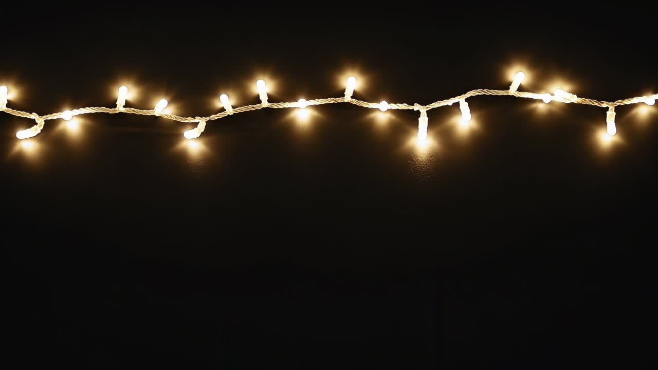 A string of warm white fairy lights against a dark background, captured from a straight-on angle