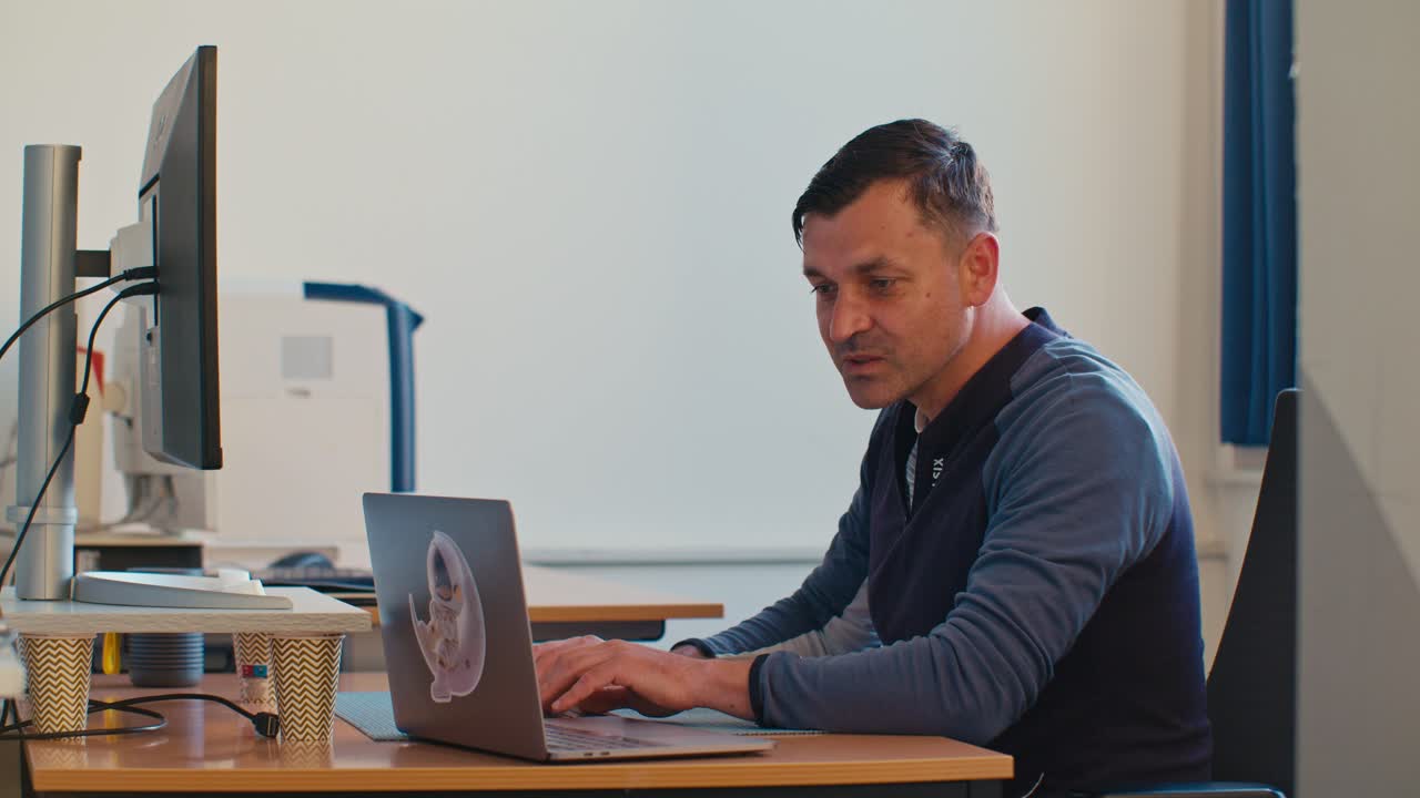 European Dutch Caucasian white man male adult model working in the office job on desktop workspace and typing on PC laptop notebook keyboard, digital film look