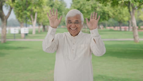 Happy-Indian-old-man-saying-hello-and-waving-hand-in-park