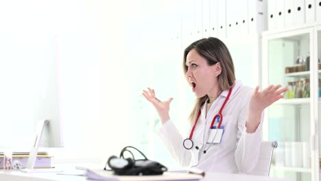 frustrated female doctor shouting and gesturing at computer in medical office