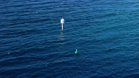 Una-Alta-Boya-Blanca-Se-Balancea-En-Medio-Del-Agua-Azul-Profunda-Del-Océano-Con-Crestas-Blancas.