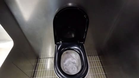 person flushing a toilet in a public restroom