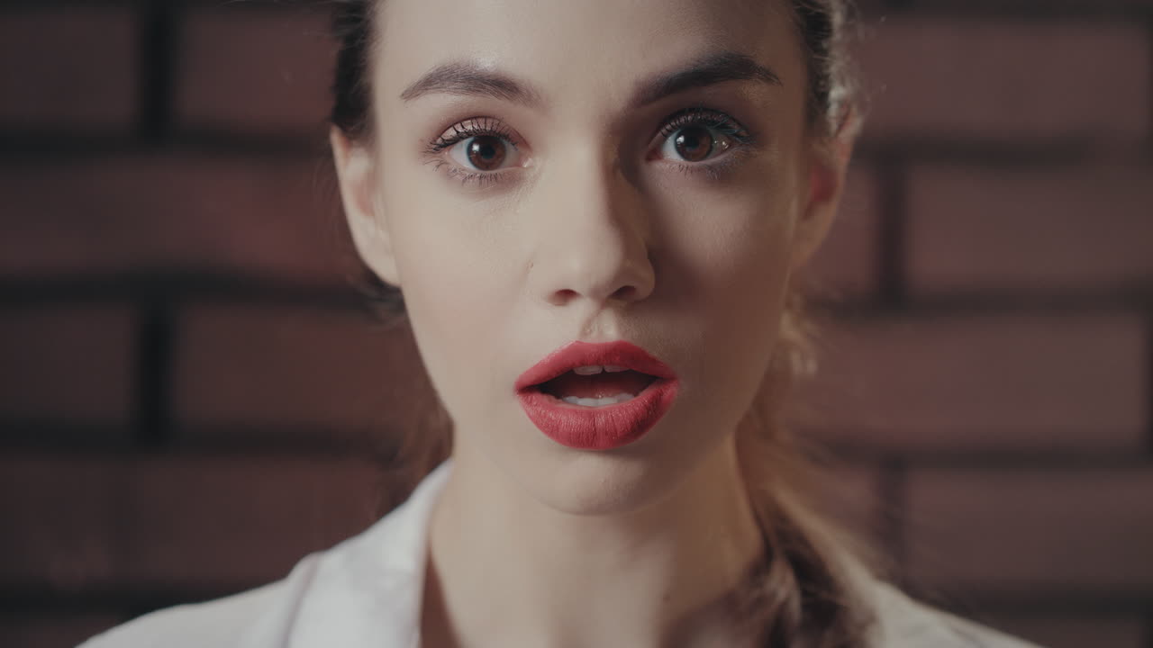 mujer sorprendida abrió la boca de asombro en el fondo de la pared de ladrillo