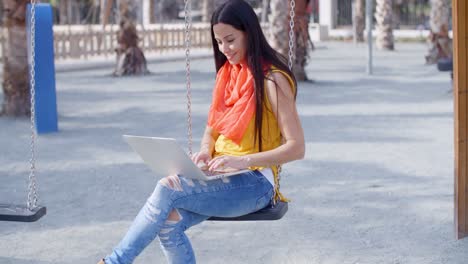 Mujer-Elegante-Sentada-En-Un-Columpio-Con-Su-Computadora-Portátil