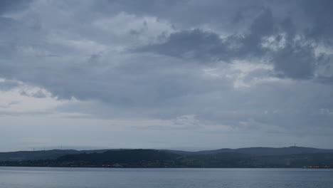 timelapse of sea and sky and distant town, the rain comes in