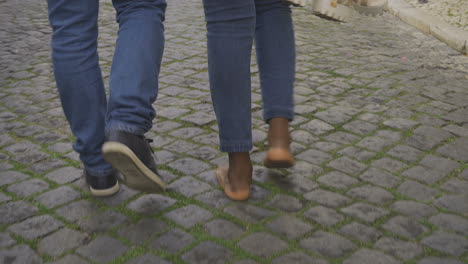 una foto cortada de un joven caminando con una mujer descalza.