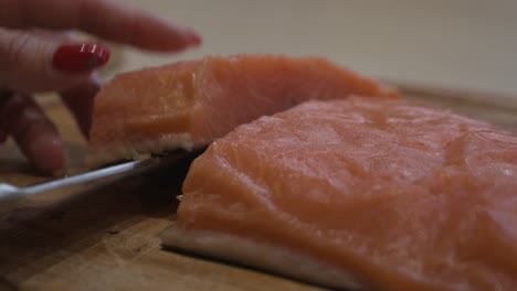 slicing salmon fillet with a kitchen knife - closeup