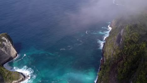 great aerial view flight panorama overview drone shot over clouds very high kelingking beach at nusa penida in bali indonesia is like jurassic park cinematic nature cliff view above by philipp marnitz