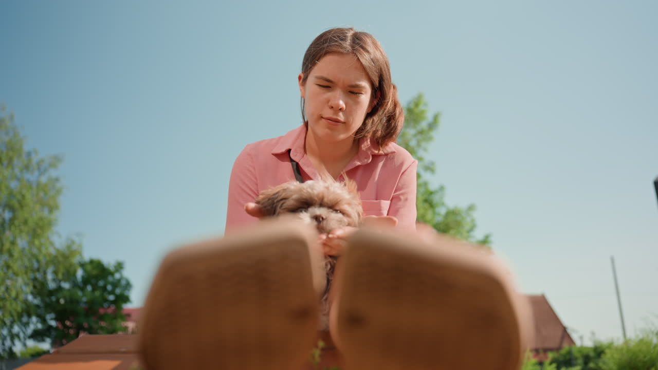 Gentle Woman Holds Small Puppy Outside, Serene Image Of Woman Caring For Tiny Dog On Park Bench, Tranquil Outdoor Setting With Woman Tenderly Holding Her Puppy Amidst Greenery And Blue Sky