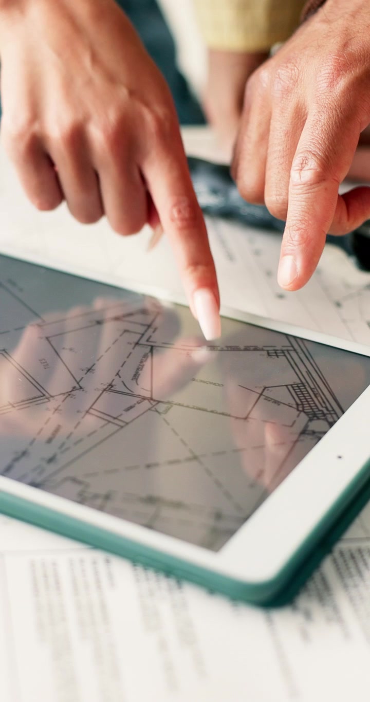 Architects Reviewing Construction Blueprints on Digital Tablet