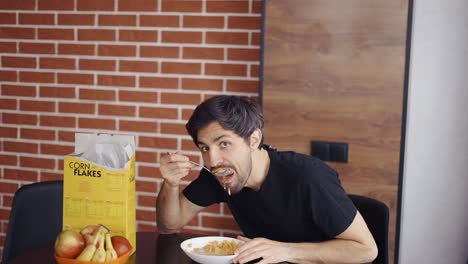 un tipo tomando copos de maíz, posando graciosamente para la cámara.