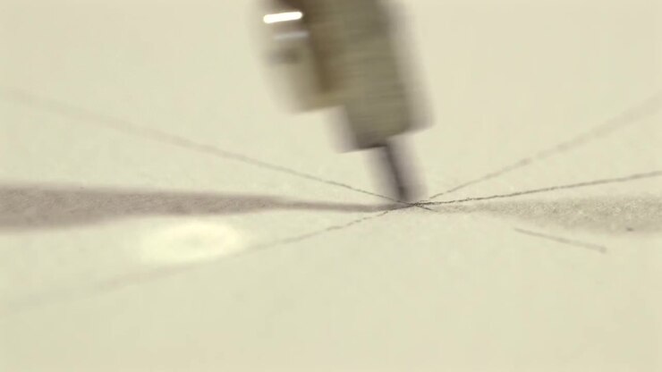 Extreme macro close-up of a metal compass drawing a circular arc on white paper. Precision drafting, geometry and technical design concept with shallow depth of field.