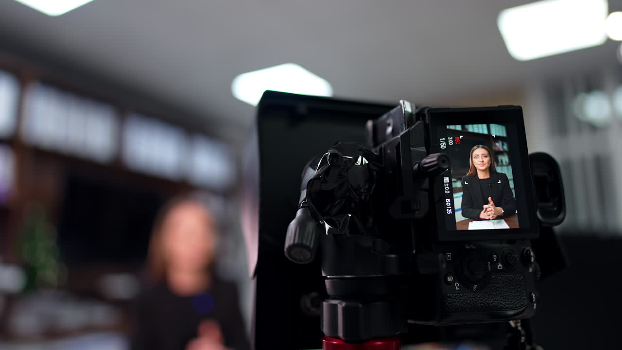 Beautiful long-haired brunette speaks to camera gesturing with hands. Close up view on the display of camera. Low angle view. Blurred backdrop.