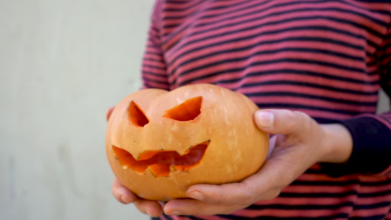 manos sosteniendo calabaza malvada con sonrisa y ojos cortados, artesanías y preparativos para haloween