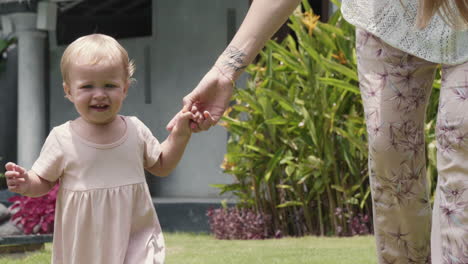 baby daughter walking with mommy outdoors