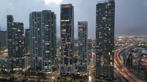 el horizonte aéreo del centro de miami iluminado por la noche con la carretera de tráfico y el rascacielos edificio moderno al atardecer en la ciudad metropolitana de florida
