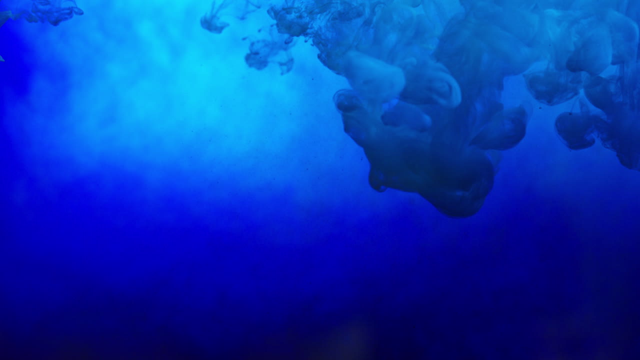 파란색 페인트 또는 염료가 색 배경에 물에 떨어지면 회전하는 다채로운 연기 배경을 만니다.