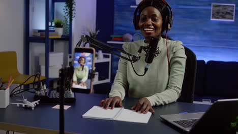 Smiling-influencer-african-woman-sitting-in-front-of-phone-camera-recording