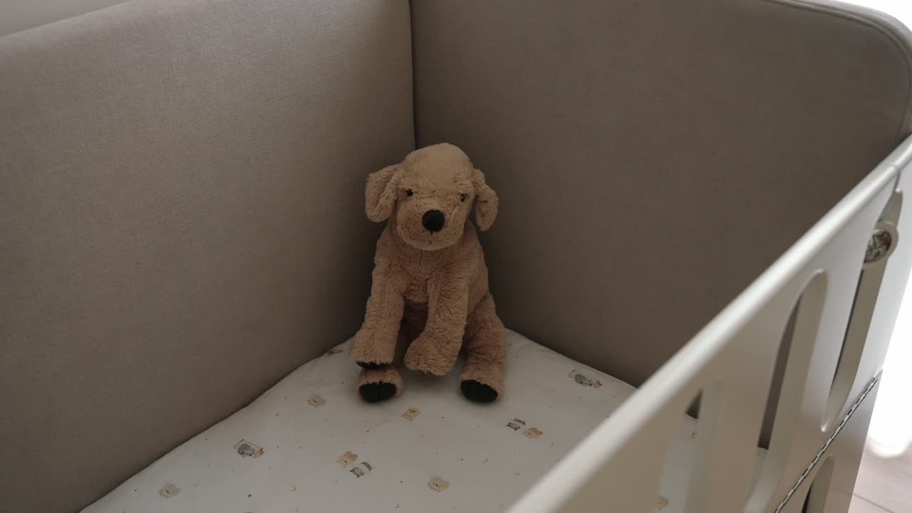 Soft plush dog toy sitting alone in a baby crib, evoking warmth and nostalgia