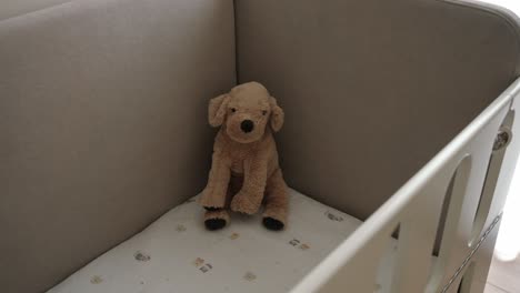 soft plush dog toy sitting alone in a baby crib, evoking warmth and nostalgia