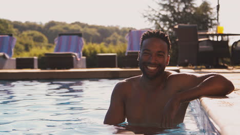 Portrait-Of-Smiling-Man-On-Summer-Holiday-Or-Vacation-Relaxing-In-Swimming-Pool