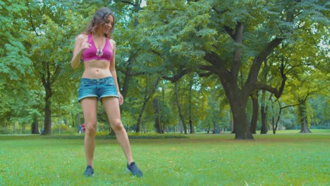 petite caucasian girl showing zumba dance moves on grass in public park