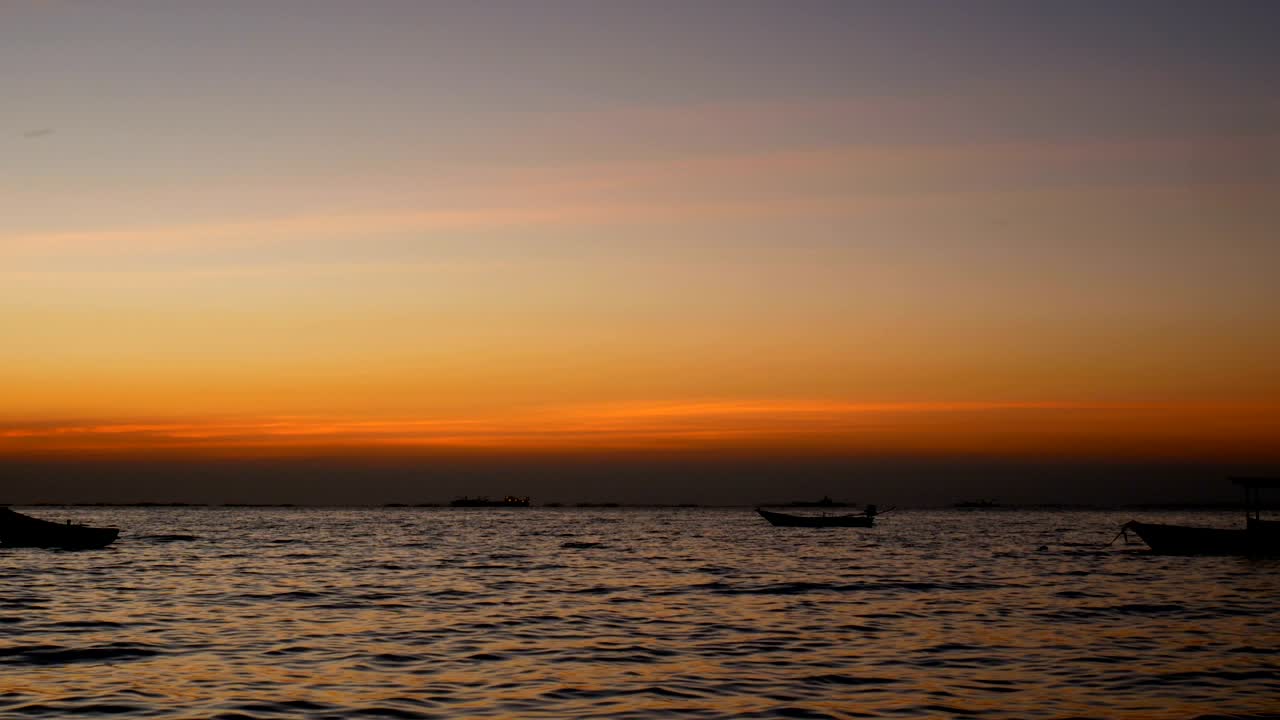 해가 지는 시간이나 해가 뜨는 시간에 작은 파도와 함께 바다 위에 작은 배의 실루, 아름다운 빛이 물 표면에 반사됩니다.
