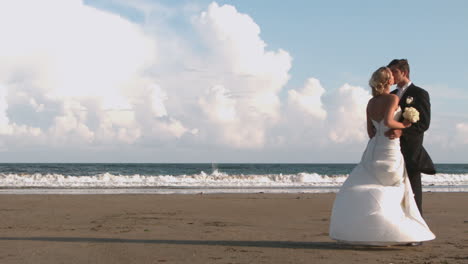 attractive newlywed couple kissing on the beach