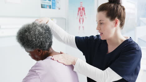 Mujer-Mayor-Diversa-Ejercitando-Cuello-Y-Doctora-Asesorando-En-El-Hospital,-Cámara-Lenta