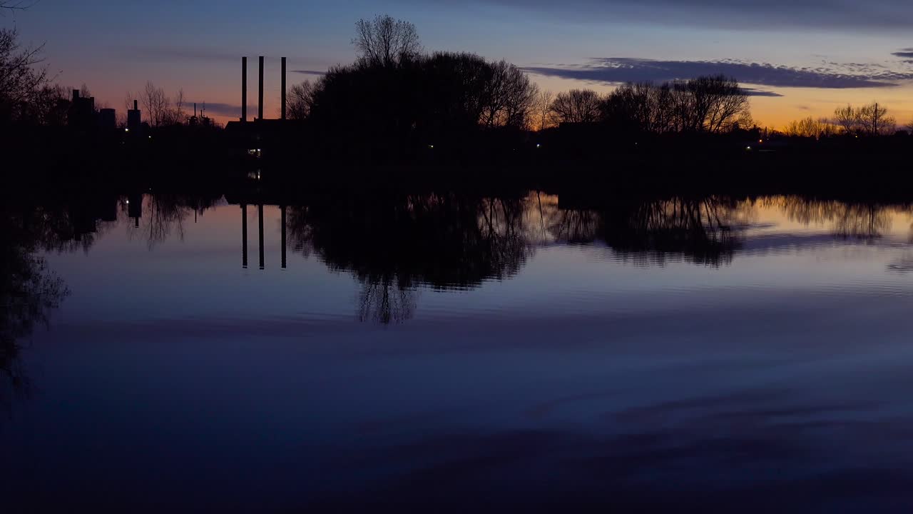 profundo atardecer en un hermoso lago que refleja las chimeneas de la industria y la contaminación distante
