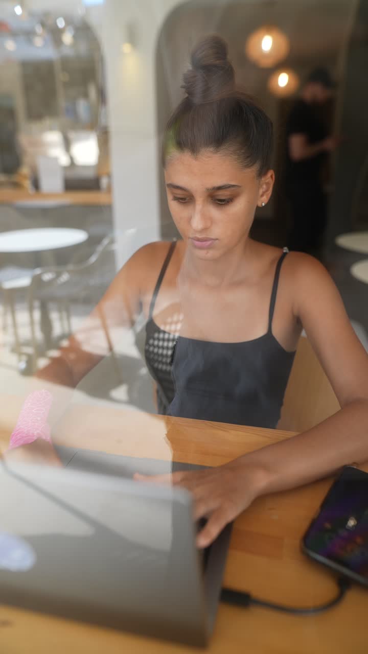 mujer joven trabajando en una computadora portátil en un café
