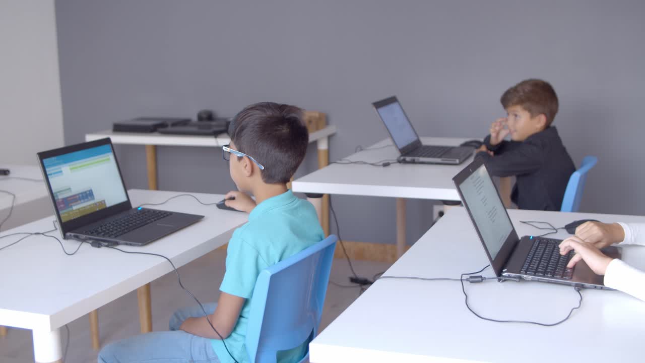 niños sentados en escritorios con computadoras portátiles en el aula