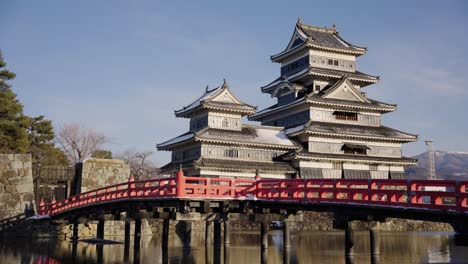 matsumoto castle in winter, snow on roof as sun sets over moat, japan