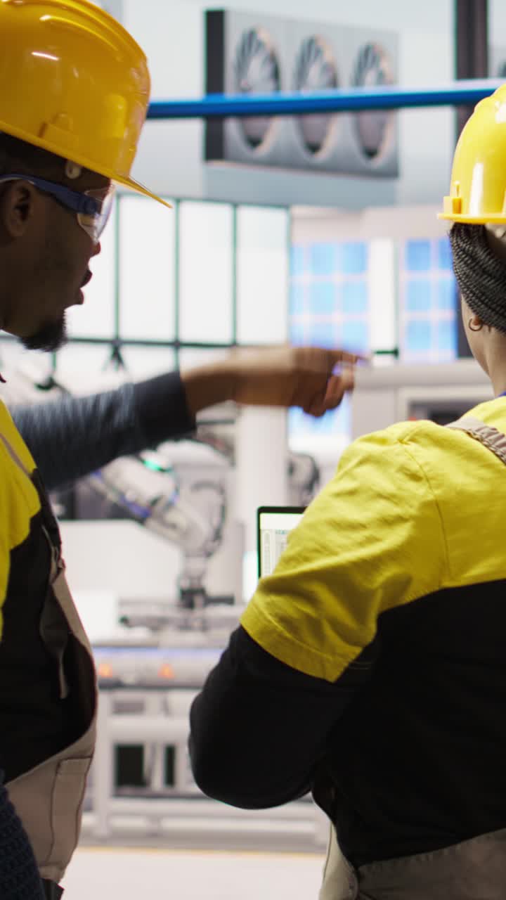 Vertical video IT staff members overseeing solar panel production lines equipment