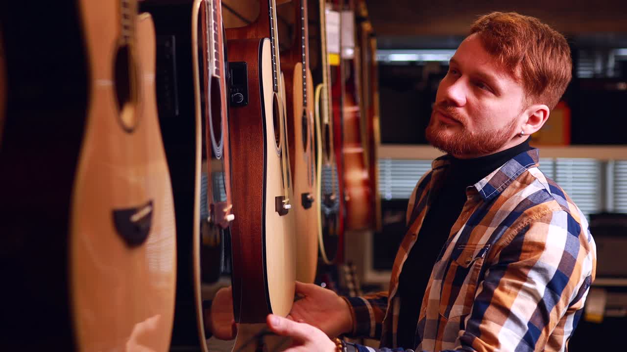 l'uomo rosso sta scegliendo una chitarra acustica di qualità nel negozio di chitarre.
