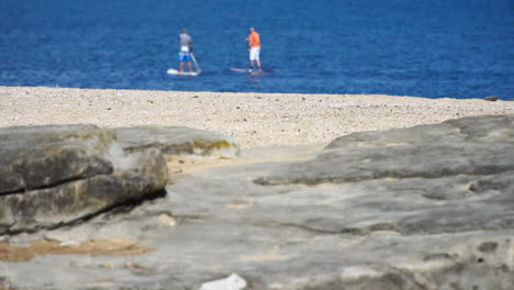 two men paddleboarding in calm ocean waters