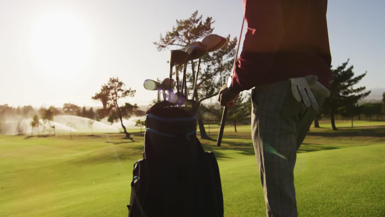 Video van de middensectie van een Afro-Amerikaanse man die golfclubs in een tas doet op de golfbaan
