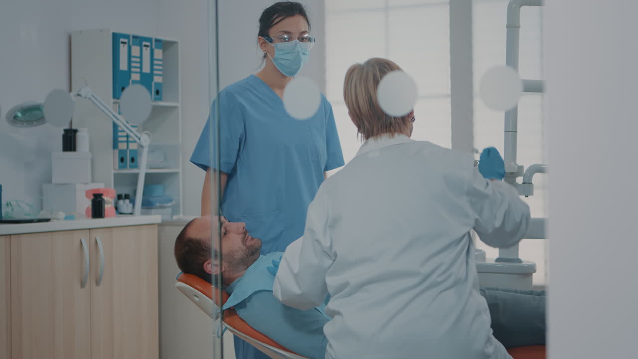 médico y enfermera examinando los dientes después de un procedimiento de cuidado bucal