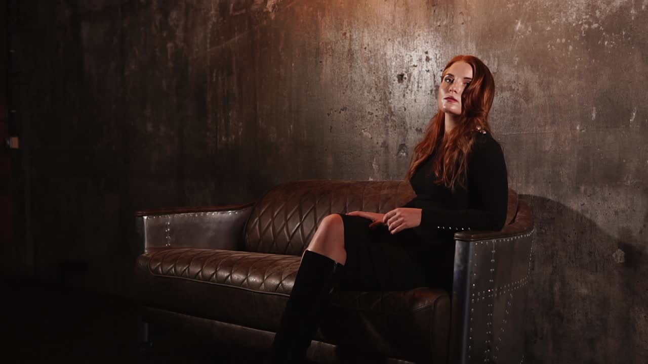 mujer con vestido negro en sofá de cuero