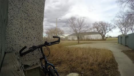 time lapse - old bicycle leaning against a house in the front yard of a house in the country as the clouds fly by