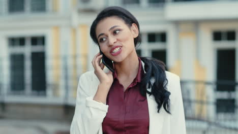 Mujer-De-Negocios-Sonriente-Hablando-Por-Teléfono-Afuera.-Mujer-De-Raza-Mixta-Llamando-Al-Aire-Libre