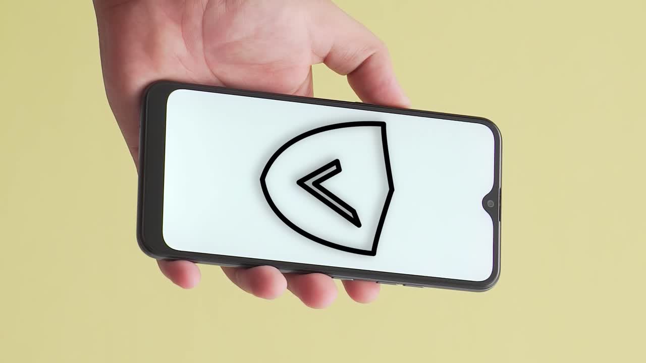 Mão mostra telefone com escudo e símbolo de verificação na tela, vertical.